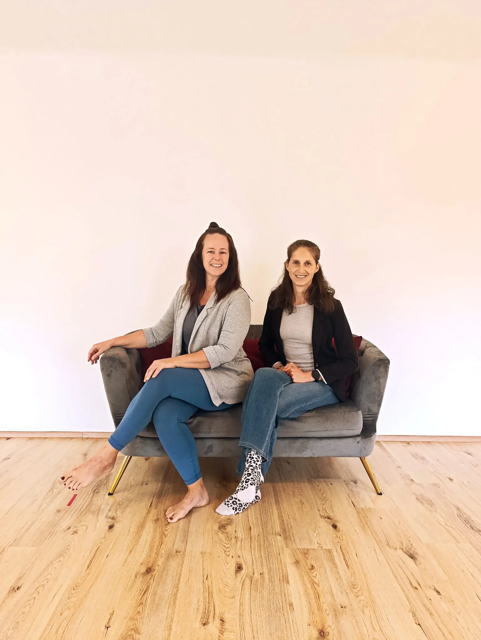 Anschi und Madlen sitzen lachend auf einem Sofa