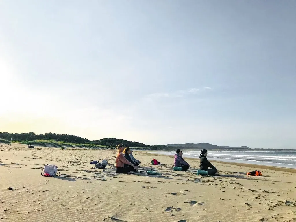 Meditation in kleiner Gruppe am Strand bei Sonnenaufgang