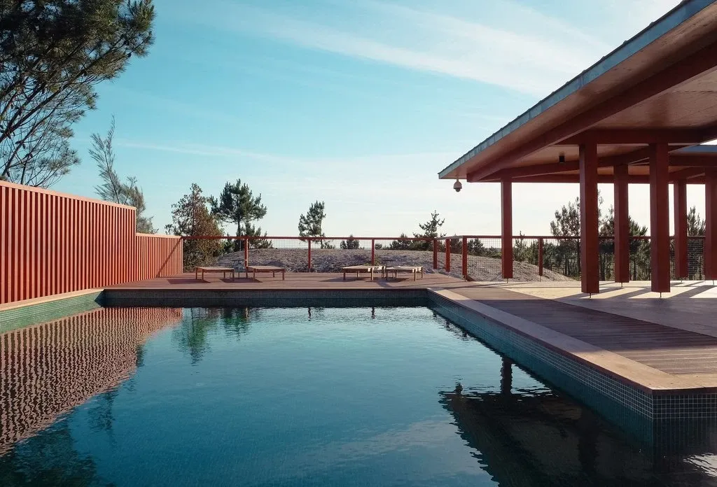 Pool mit Sonnenliegen zwischen Pinien
