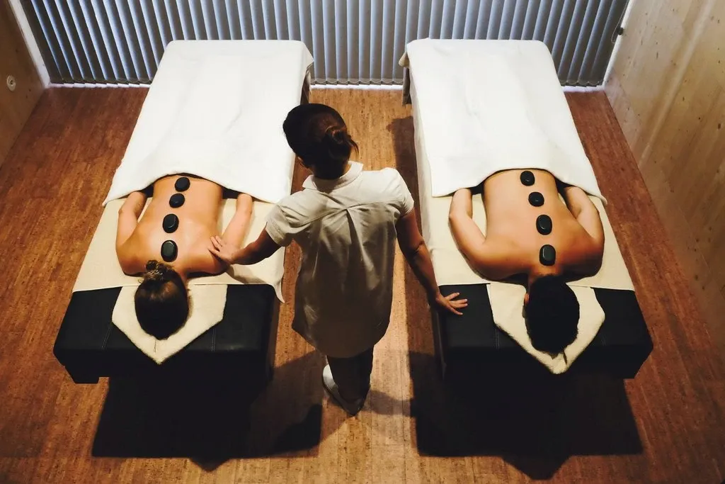 Massage mit warmen Steinen auf zwei Liegen
