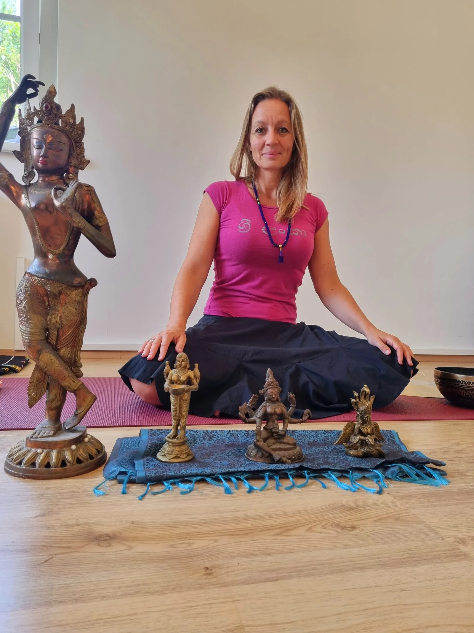 Shakiri sitzt auf der Yogamatte zwischen indischen Statuen